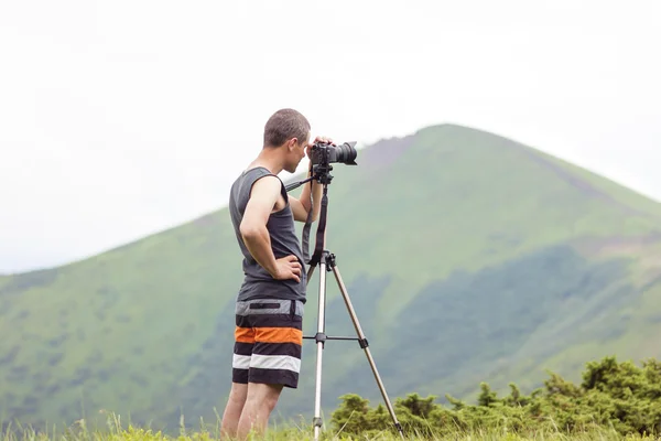 Fotografo con una macchina fotografica su treppiede che fotografa le montagne — Foto Stock