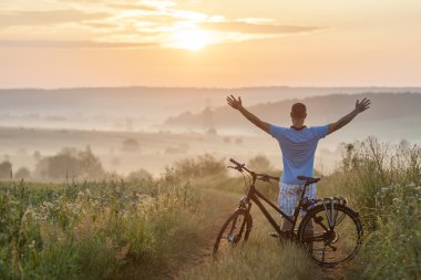 Sabah Sunrise seninki ile ayakta Bisiklet yakınındaki genç adam