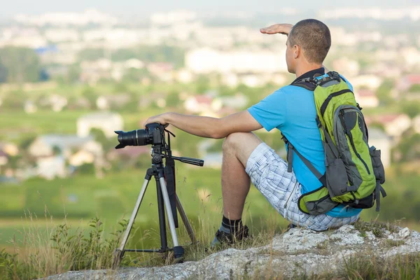 Tramp fotograf sedí na skále Těšíme se poblíž cam — Stock fotografie