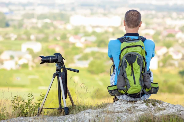 Hiker photographer  sitting on a rock looking forward near a cam