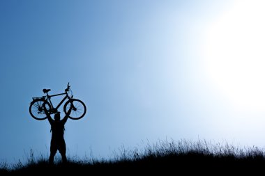 Bisiklet mavi gökyüzü üzerinde tutan bir adam silüeti