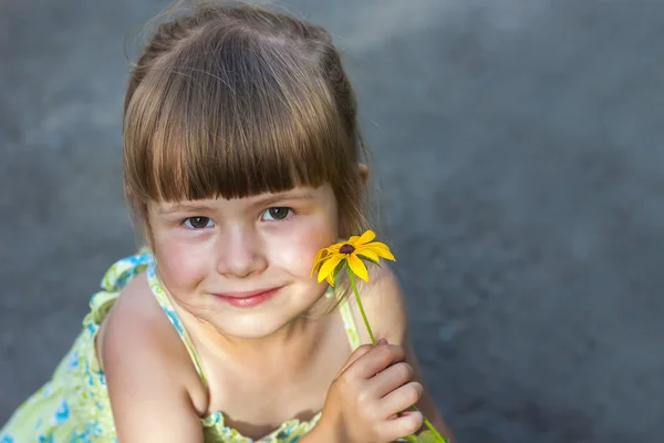 Söt leende liten flicka håller gul blomma — Stockfoto