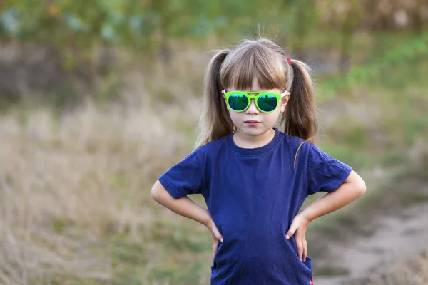 Porträtt av lilla fashionabla flicka i gröna solglasögon utomhus — Stockfoto