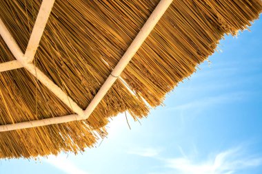 Mavi gökyüzüne karşı sarı saman çatının detaylarını kapat.