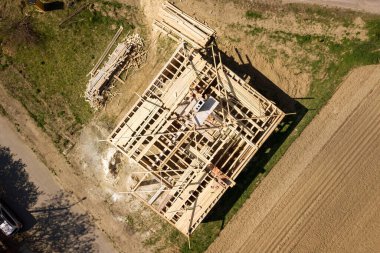 İnşaat halindeki ahşap çatı iskeleti olan bitmemiş tuğla evin havadan görüntüsü..