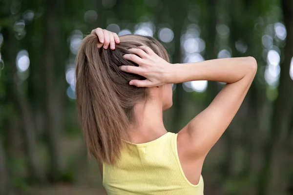 Młoda Kobieta Wiąże Długie Włosy Stojąc Zewnątrz — Zdjęcie stockowe