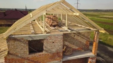 İnşaat halindeki ahşap çatı iskeleti olan bitmemiş tuğla evin havadan görüntüsü..