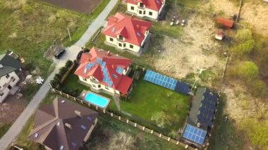 Yeşil çimlerle kaplı özel bir evin havadan görünüşü çatıda güneş panelleri, mavi su ve rüzgar türbini jeneratörlü yüzme havuzu..