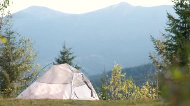 Kamp alanında duran boş bir kamp çadırı. Uzakta görkemli yüksek dağ zirveleri var. Vahşi doğada yürüyüş ve aktif iz sürme konsepti.