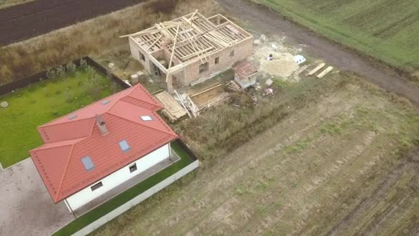 Top down aerial view of two private houses, one under construction with wooden roofing frame and another finished with red tiled roof. — Stock Footage Top Aerial View Two Private Houses One Construction Wooden Roofing Royalty Free Stock Video