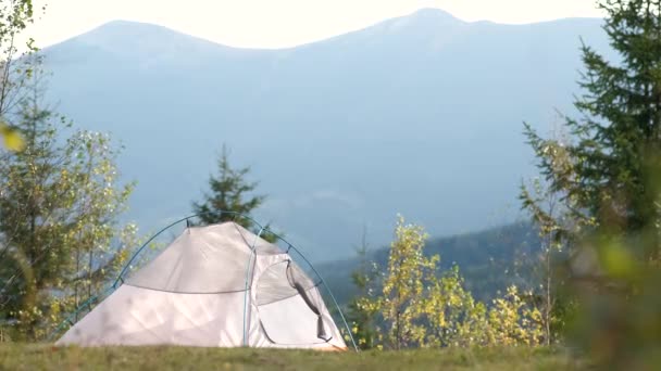 遠くに雄大な高い山の峰を眺めながらキャンプ場に立つ空のキャンプテント 野生の自然とアクティブなトレイルの旅のコンセプトでハイキング — ストック動画