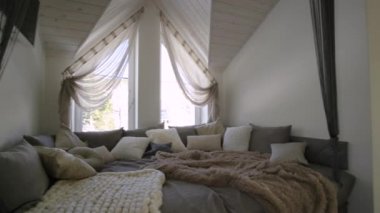 Modern bir evin içi geniş bir koridor ve büyük yumuşak bir dinlenme yeri. Çağdaş geniş kanepe, çok yastıklı ve pencereli ahşap tavan..