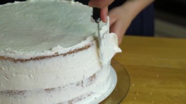 Kadın ellerine yakın beyaz krema ve bisküviyle tatlı pasta yapıyor..