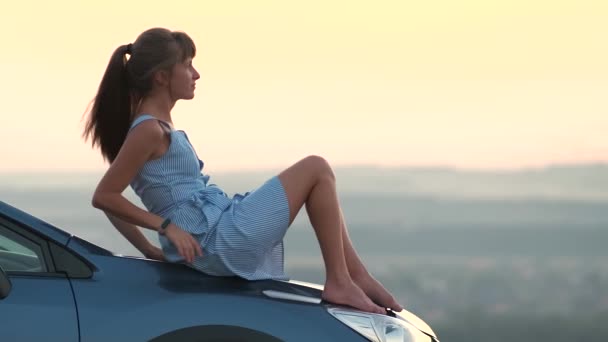 Щаслива Жінка Водій Відпочиває Капоті Своєї Машини Насолоджуючись Видом Захід — стокове відео