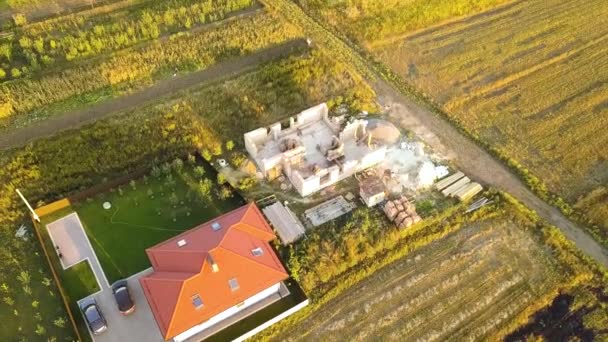 Top down aerial view of two private houses, one under construction with wooden roofing frame and another finished with red tiled roof. — Stock Footage Top Aerial View Two Private Houses One Construction Wooden Roofing Stock Video