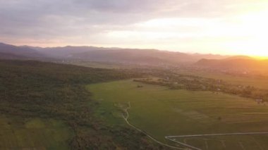 Nadvirna kasabasının hava manzaralı yeşil tepelerde dağınık küçük evler ve gün batımında uzak Karpat dağları..