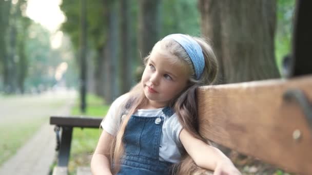 小女孩一个人坐在夏季公园的长椅上 — 图库视频影像