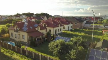 Çatıda güneş panelleri ve temiz ucuz elektrik üretmek için rüzgar jeneratörü olan otonom bir evin havadan görüntüsü..