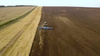 Sonbaharda hasattan sonra tarla süren bir traktörün hava görüntüleri..