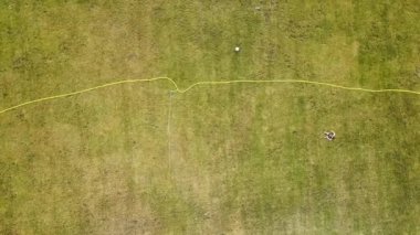 Yeşil çimenler ve su püskürten fıskiyelerle kaplı futbol sahası yüzeyinin yukarıdan görünüşü.