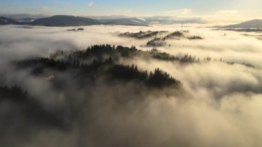 Güneşin doğuşuyla sisli dağlarda tepedeki küçük köy evlerinin hava manzarası..