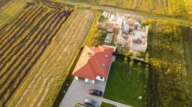 Biri ahşap çatı iskeleti ve diğeri de kırmızı kiremit çatılı iki özel evin yukarıdan aşağıya bakan görüntüsü..