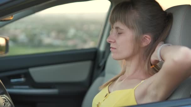 若い女性ドライバーが車の車輪の後ろに休んでいる — ストック動画