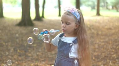 Yeşil Park 'ın dışında sabun köpüğü üfleyen mutlu küçük kız çocuğu. Çocuklar için açık hava yaz aktiviteleri.
