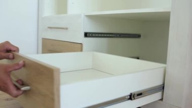 Erkek marangoz ellerinin mobilya dolabını monte etmesi ve yeni ahşap çekmece takması..