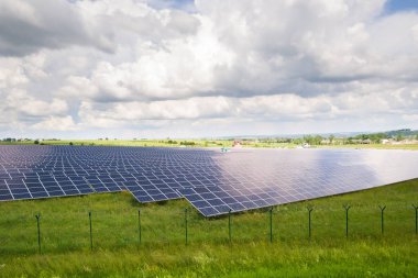 Yeşil alandaki güneş enerjisi santralinin koruyucu tel örgülü havadan görüntüsü. Temiz ekolojik enerji üretmek için elektrik panelleri.