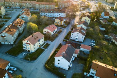 Kırsal kesimde kırmızı çatısı olan evleri ve park halindeki arabaları olan caddeleri gösteren hava manzarası. Modern bir Avrupa şehrinin sessiz banliyöleri.