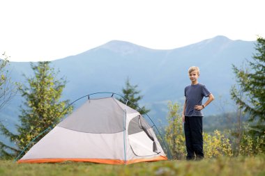 Mutlu çocuk dağ kampında bir turist çadırında dinleniyor ve güzel yaz manzarasının tadını çıkarıyor. Yürüyüş ve aktif yaşam biçimi.