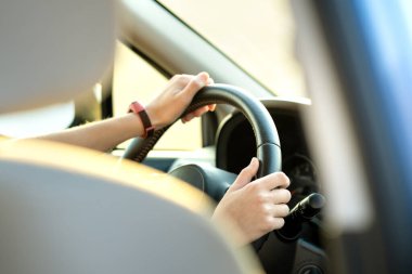 Güneşli bir günde şehir caddesinde direksiyon başında araba süren kadın elleri yakın çekim görüntüsü..