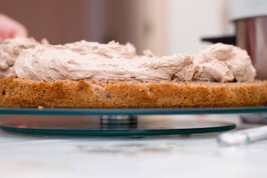 Evde kek pişirme süreci. Çikolatalı bisküvinin üzerine kadın el kreması dök. Mutfak ve lezzetli tatlı konsepti.