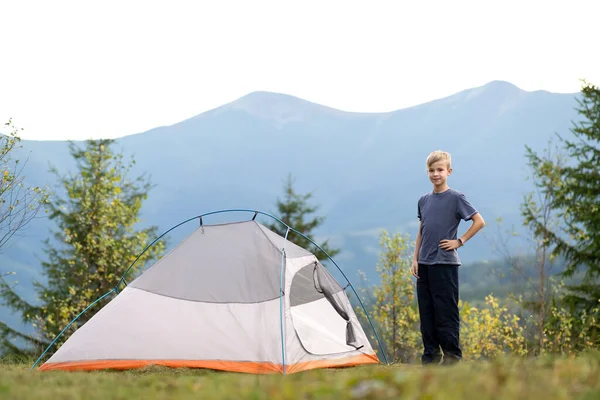 Mutlu çocuk dağ kampında bir turist çadırında dinleniyor ve güzel yaz manzarasının tadını çıkarıyor. Yürüyüş ve aktif yaşam biçimi.