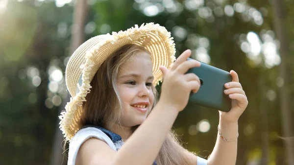 Glücklich Lächelndes Kindermädchen Das Sommer Draußen Mit Seinem Handy Zusieht — Stockfoto