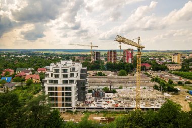 Kule görüntüsü, vinç kaldırma ve inşaat halindeki uzun apartmanın beton iskeleti. Kentsel kalkınma ve gayrimenkul büyüme kavramı.