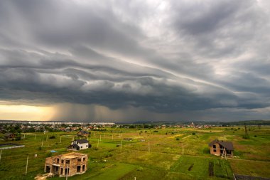 Kara fırtınalı bulutlarla kapkara bir manzara Yazın uzak kasaba binalarının üzerine sağanak yağmur yağıyor.