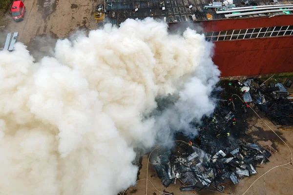 Aerial view of firemen fighting with fire near old factory biulding in industrial area.