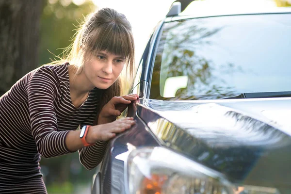 それを購入する前にディーラーの屋外店で新しい車をよく調べる若い女性の顧客 — ストック写真