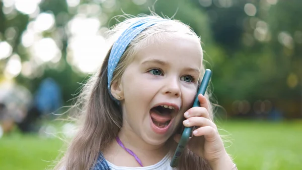 夏の公園で彼女の携帯電話で会話をしているかなり小さな子供の女の子 — ストック写真