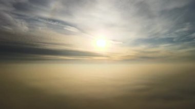 Üzerinde mavi gökyüzü olan beyaz yoğun bulutların üzerinde parlak sarı günbatımının havadan görünüşü.