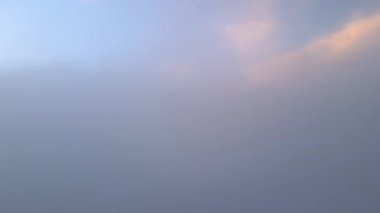 Parlak gündoğumunda beyaz yoğun bulutların üzerinde büyük bir dağın havadan görünüşü.