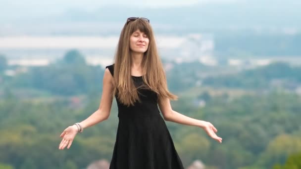 穿着黑色短裙站在山顶上享受夏日温暖的长发女子 — 图库视频影像