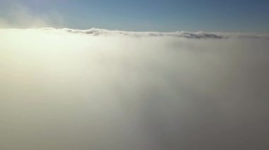 Parlak güneşli bir günde, beyaz kabarık bulutların yukarıdan görünüşü.