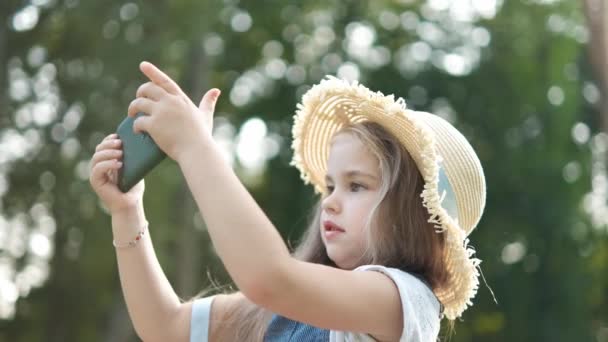 Glücklich Lächelndes Kindermädchen Das Sommer Draußen Handy Sucht — Stockvideo