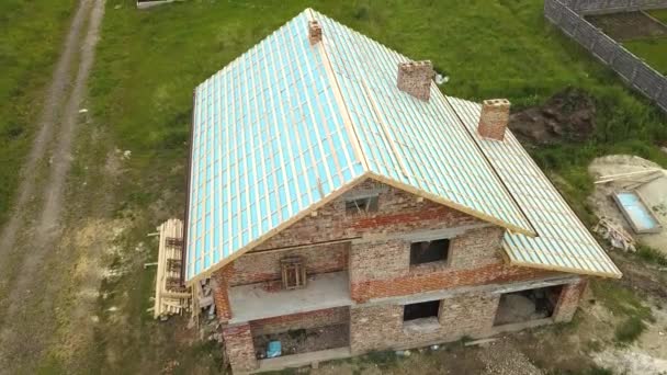 Letecký pohled na cihlový dům s dřevěným střešním rámem ve výstavbě.