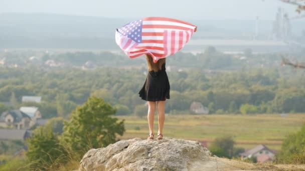 年轻美丽的美国女人 长发飘扬 飘扬着美国国旗 站在室外享受夏日的温暖 — 图库视频影像
