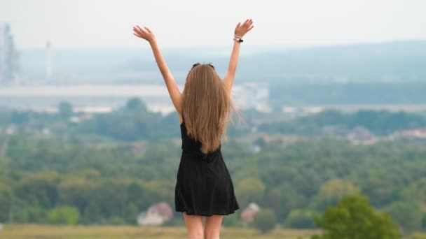 一个身穿夏装的精力充沛的年轻女子在山顶上快乐地跳舞的背影 — 图库视频影像