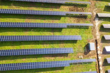 Yeşil alanda inşa halindeki güneş enerjisi santralinin havadan görüntüsü. Temiz ekolojik enerji üretmek için elektrik panellerinin montajı.